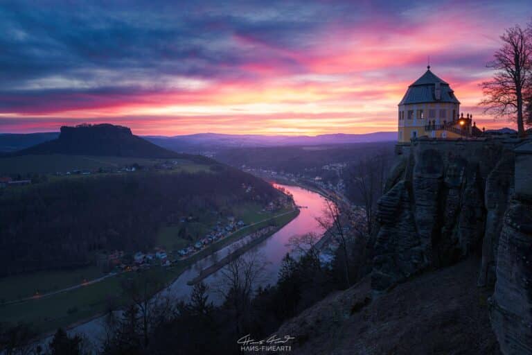 Blick von der Festung Königstein Richtung Friedrichsburg und Lilienstein vor Sonnenaufgang, mit rot-violett leuchtendem Himmel.