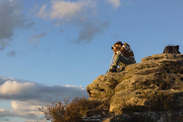 Ein Teilnehmer sitzt auf einem Felsvorsprung auf dem Gamrig und fotografiert den Sonnenuntergang.